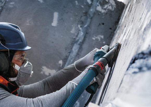 Object #200573502: 7743905_app_wide_2 Person wearing safety equipment grinds a concrete wall with a power tool.