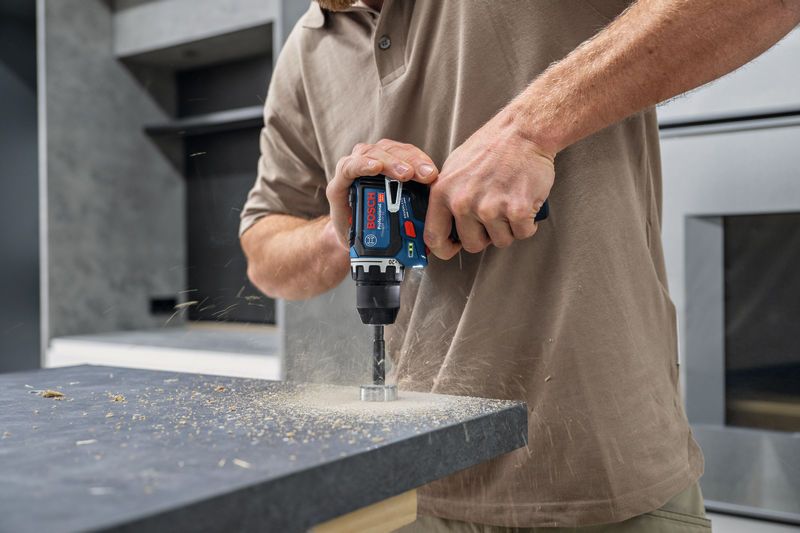 A person drills a hole into a countertop with a cordless power tool.