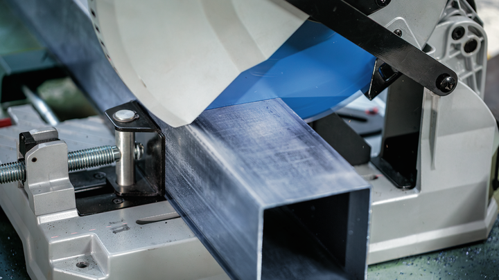 Object #200585211: 7557706_app_web_05 Metal cutting saw slices through a large steel beam in an industrial setting.