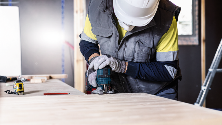 EXPERT ‘Wood 2-side clean’ T 308 B Jigsaw Blade 5-pc Person wearing safety equipment uses a power tool to cut wood at a workbench.