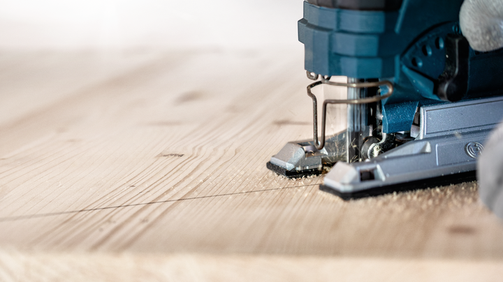 Object #200597867: 2793296_app_web_01 Person guides a jigsaw along a marked line cutting a wooden plank.
