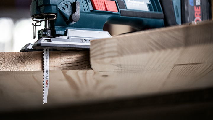 Object #200597871: 2793296_app_web_04 Jigsaw cutting through a thick wooden board in a workshop.