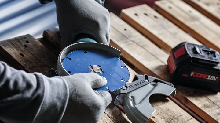 Person wearing safety equipment attaches a circular saw blade to a power tool.