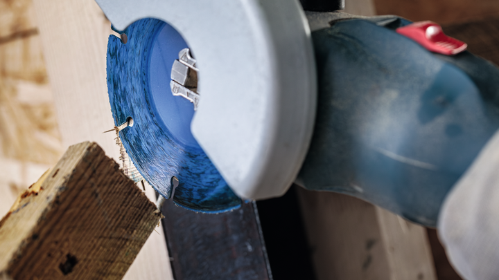 Circular saw blade cuts through a wooden board in a workshop.