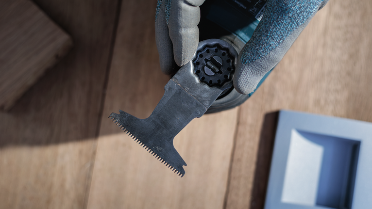 Person wearing safety equipment attaches a saw blade to a power tool.